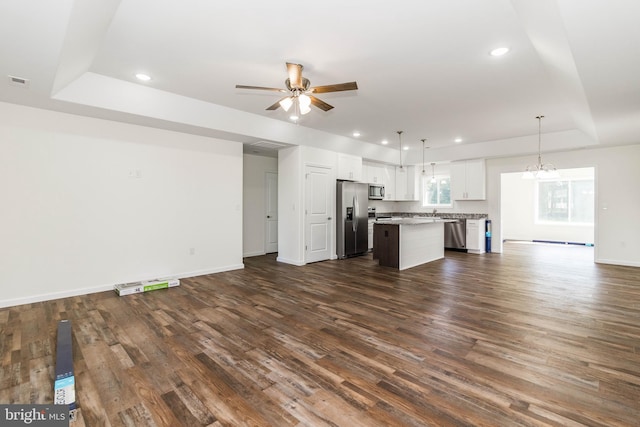 unfurnished living room featuring ceiling fan, a tray ceiling, and dark hardwood / wood-style floors