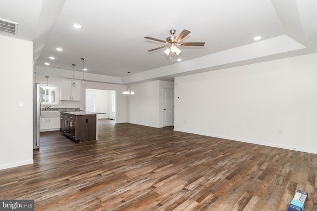 unfurnished living room with sink, dark hardwood / wood-style floors, and ceiling fan with notable chandelier