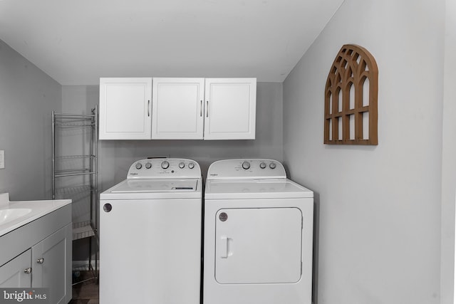 clothes washing area featuring cabinets and separate washer and dryer