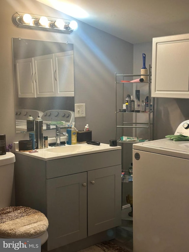 bathroom with toilet, washer / clothes dryer, and vanity