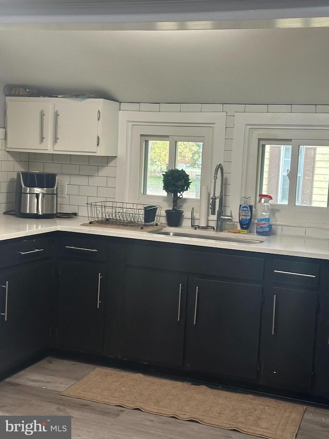 kitchen featuring white cabinetry, sink, backsplash, and light hardwood / wood-style floors