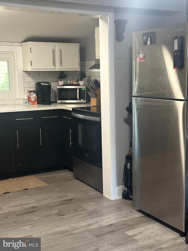 kitchen featuring tasteful backsplash, white cabinetry, appliances with stainless steel finishes, and light wood-type flooring