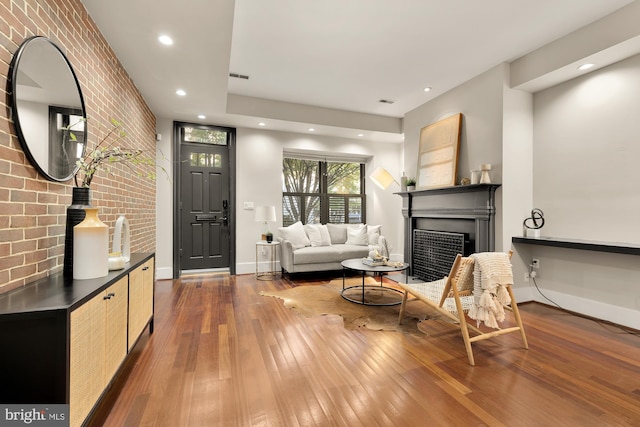 living room featuring dark wood-type flooring and brick wall