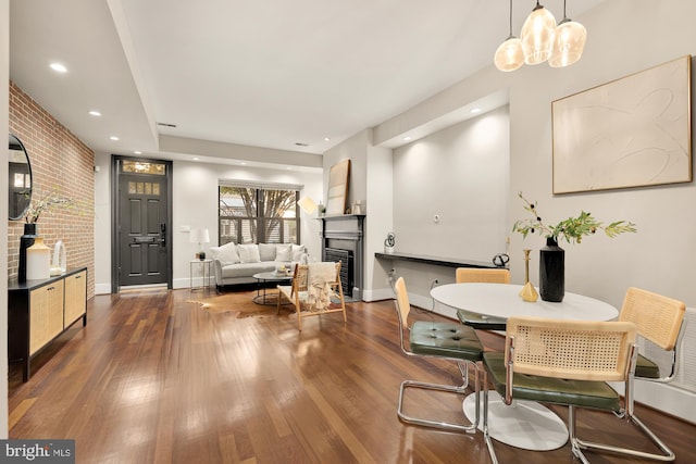 dining area with dark hardwood / wood-style floors and brick wall