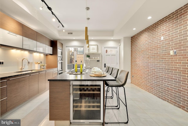 kitchen featuring a kitchen island, stainless steel appliances, wine cooler, brick wall, and sink