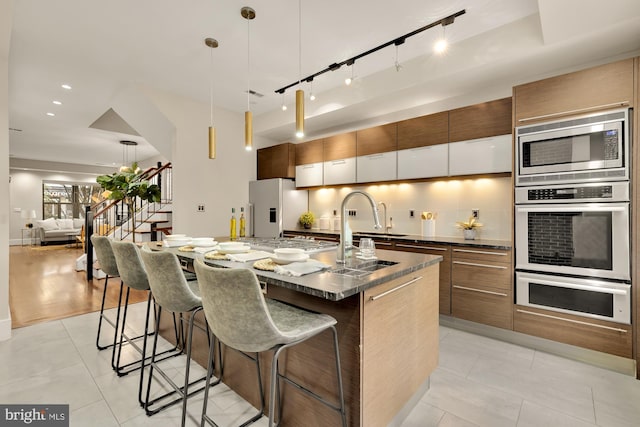 kitchen featuring a large island, light tile patterned floors, a kitchen bar, decorative light fixtures, and white refrigerator with ice dispenser