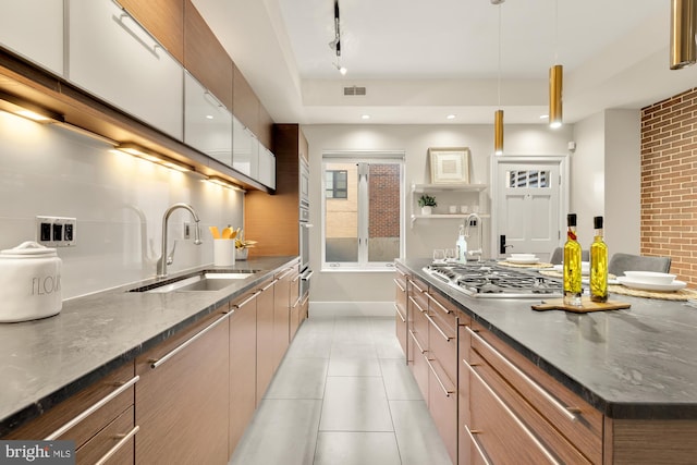 kitchen featuring appliances with stainless steel finishes, sink, hanging light fixtures, white cabinetry, and dark stone counters