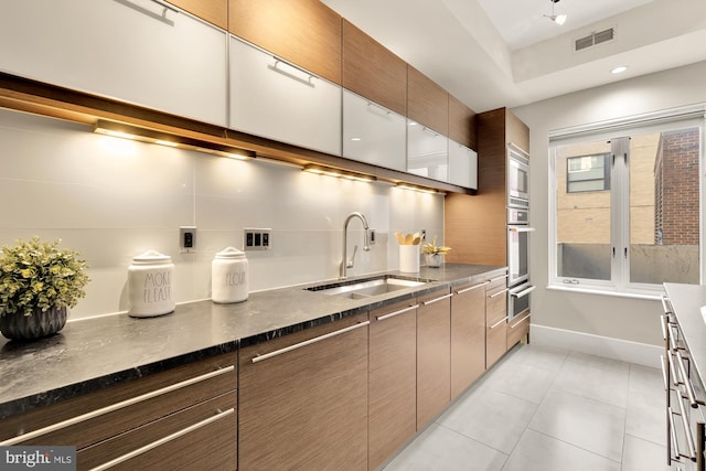 kitchen featuring light tile patterned flooring, decorative backsplash, sink, and stainless steel appliances