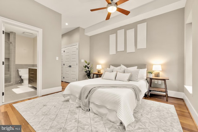 bedroom with a closet, ensuite bathroom, light wood-type flooring, and ceiling fan