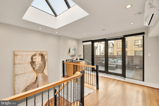 corridor with an AC wall unit, a skylight, and hardwood / wood-style floors