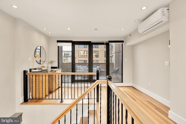 hall featuring a wall mounted air conditioner and hardwood / wood-style flooring