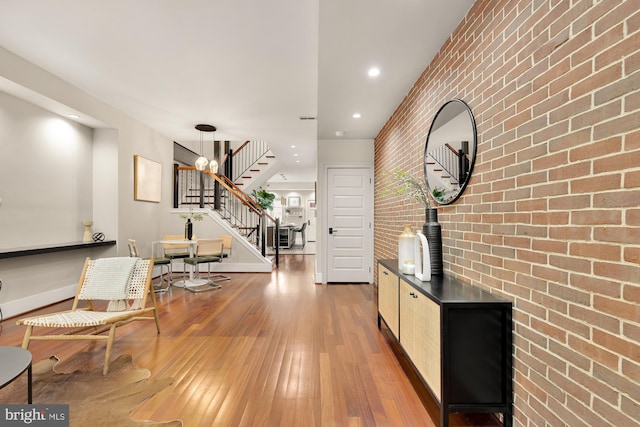 corridor with brick wall, a chandelier, and wood-type flooring