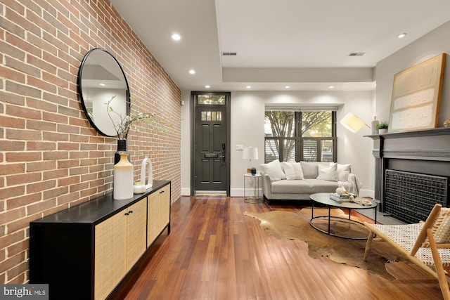 living room featuring dark hardwood / wood-style floors, a large fireplace, and brick wall