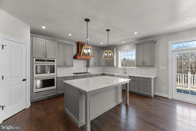 kitchen with appliances with stainless steel finishes, dark hardwood / wood-style floors, pendant lighting, and gray cabinetry