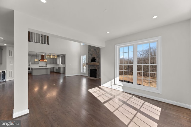 unfurnished living room with dark wood-type flooring and a stone fireplace