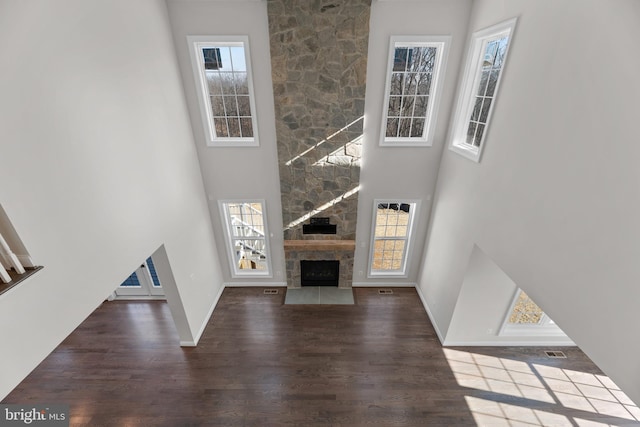 unfurnished living room featuring hardwood / wood-style flooring, a high ceiling, plenty of natural light, and a fireplace