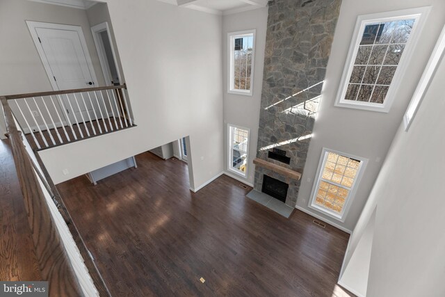 living room featuring a healthy amount of sunlight, a towering ceiling, and dark hardwood / wood-style floors