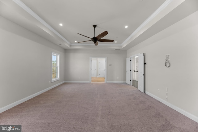 carpeted spare room with ceiling fan, a raised ceiling, and ornamental molding