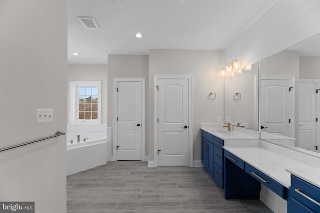 bathroom with vanity, hardwood / wood-style flooring, and a tub