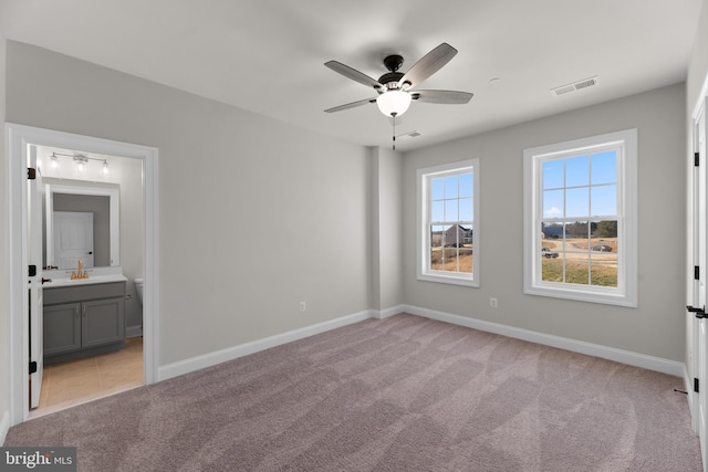 unfurnished bedroom with connected bathroom, ceiling fan, and light colored carpet