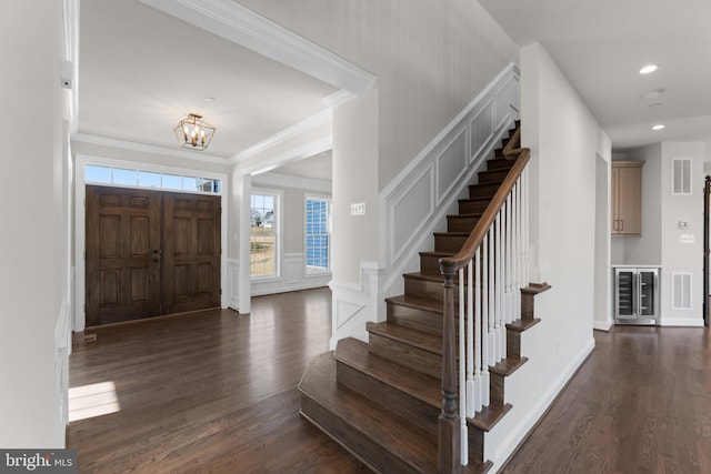 entrance foyer with ornamental molding, a notable chandelier, and dark hardwood / wood-style floors