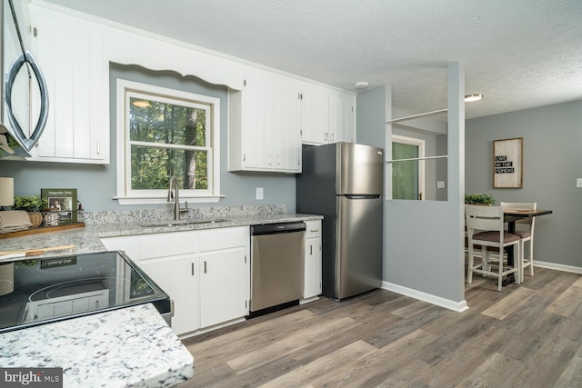 kitchen with light hardwood / wood-style floors, appliances with stainless steel finishes, a textured ceiling, and white cabinets