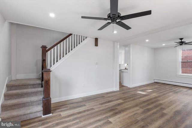 unfurnished living room featuring a baseboard heating unit, hardwood / wood-style flooring, and ceiling fan