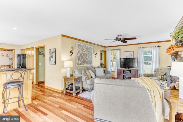 living room with crown molding, light hardwood / wood-style floors, and ceiling fan