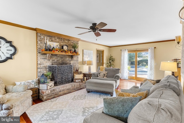 living room with crown molding, a fireplace, wood-type flooring, and ceiling fan