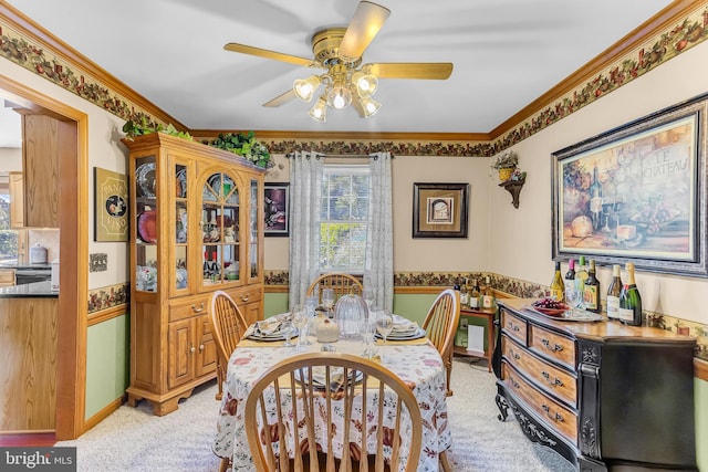 dining area featuring ornamental molding, light colored carpet, and ceiling fan