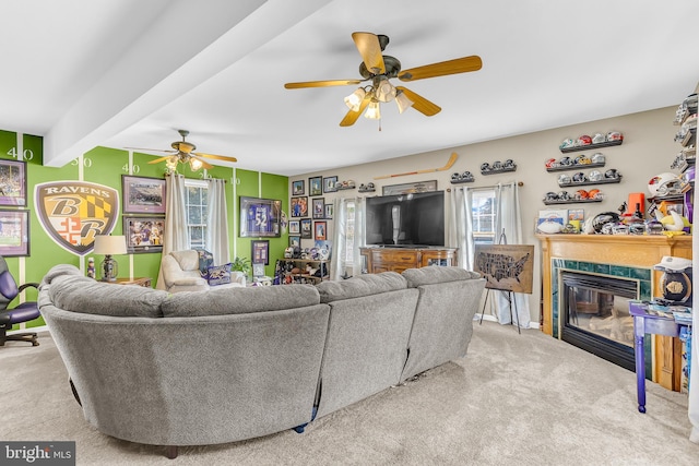 living room featuring beamed ceiling, a fireplace, light colored carpet, and ceiling fan