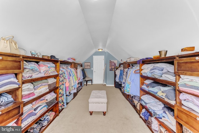 walk in closet with light carpet and vaulted ceiling