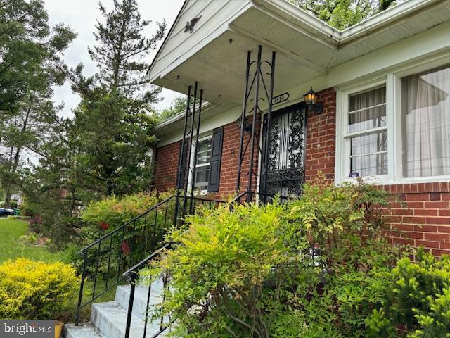 entrance to property with brick siding and a porch