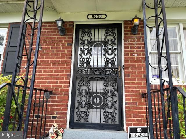 view of exterior entry with covered porch and brick siding