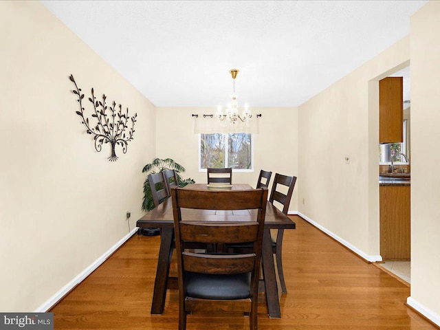 dining area featuring sink, a notable chandelier, and hardwood / wood-style flooring