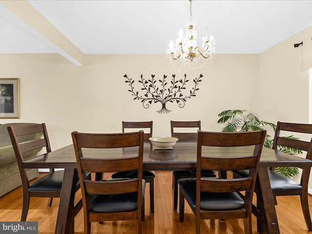 dining room with a chandelier, hardwood / wood-style floors, and beamed ceiling