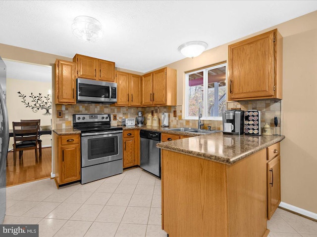 kitchen with tasteful backsplash, dark stone countertops, sink, and appliances with stainless steel finishes