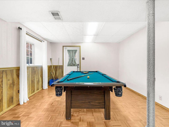 game room with light parquet floors, pool table, and wood walls