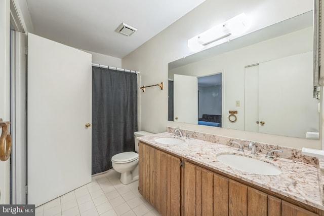 bathroom with toilet, vanity, and tile patterned flooring