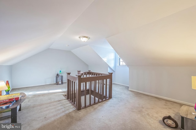 bonus room with light colored carpet and vaulted ceiling