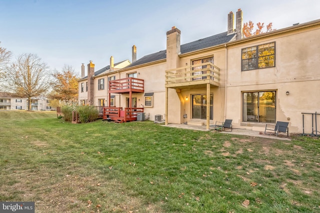 back of property with central air condition unit, a patio area, a lawn, and a balcony