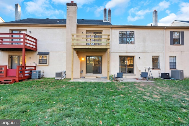 rear view of house with a balcony, central air condition unit, and a lawn