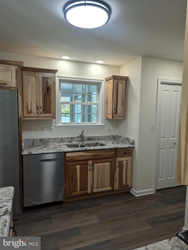 kitchen featuring appliances with stainless steel finishes, light stone counters, sink, and dark hardwood / wood-style floors