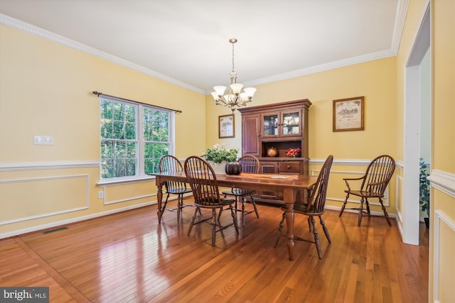 dining space with ornamental molding, a chandelier, and hardwood / wood-style flooring