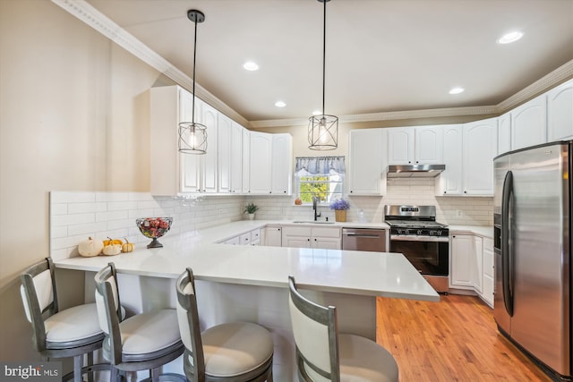 kitchen with appliances with stainless steel finishes, kitchen peninsula, hanging light fixtures, and a breakfast bar area