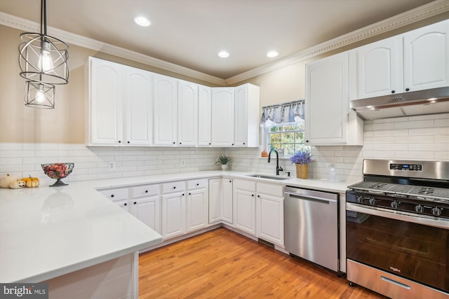 kitchen with hanging light fixtures, stainless steel appliances, ornamental molding, sink, and white cabinetry