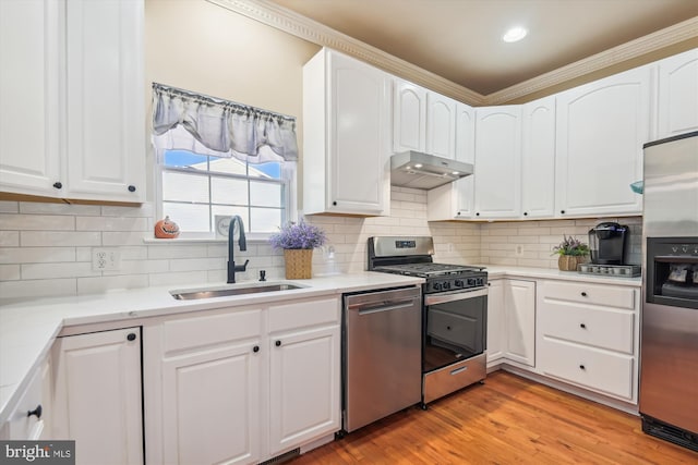 kitchen with tasteful backsplash, appliances with stainless steel finishes, sink, and white cabinets