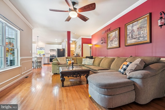 living room featuring light hardwood / wood-style floors, ornamental molding, and ceiling fan