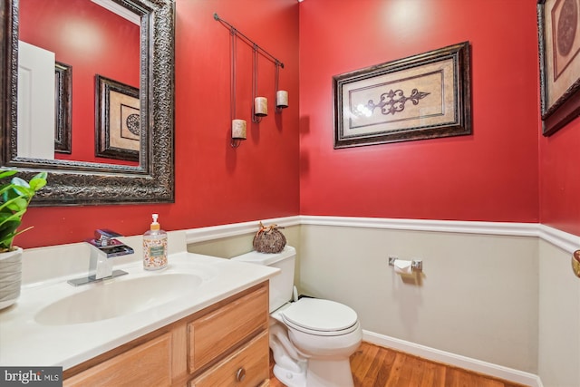 bathroom with toilet, vanity, and wood-type flooring