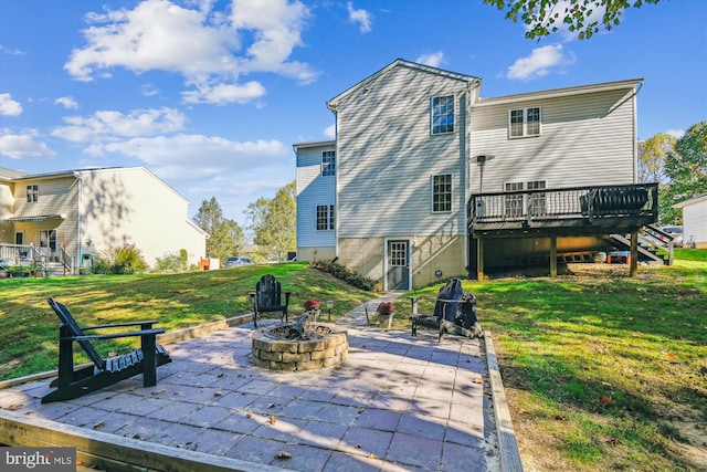 rear view of property featuring a wooden deck, a patio area, a lawn, and a fire pit